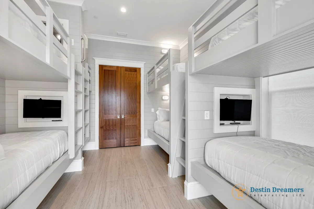 A cozy and playful bunk room with built-in bunk beds, a flat-screen TV, and a wooden door. The room is designed for fun sleepovers or extra guest accommodation and exudes a welcoming, family-friendly mood.