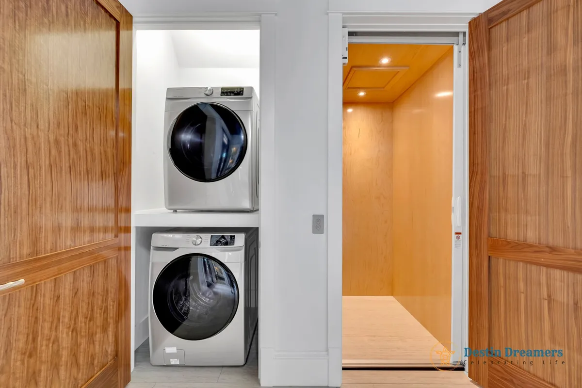 A functional laundry space featuring stacked washer and dryer units and a sliding door to an adjacent area. Clean lines and modern organization make chores easy, ensuring comfort for all guests.