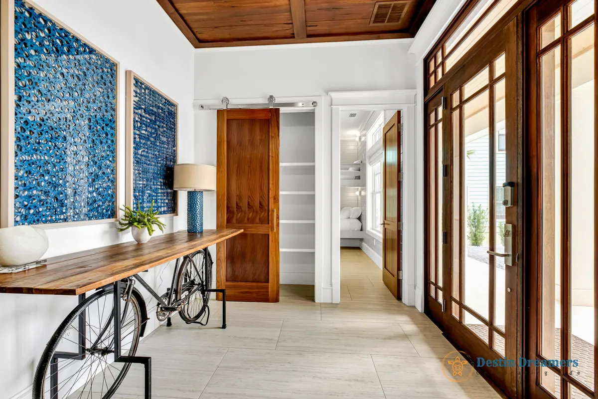 This interior shot features a stylish entryway with a wooden table, bold blue artwork, and a bicycle leaning against the wall. The space is both welcoming and practical, with the bike suggesting adventure and easy access to neighborhood trails.