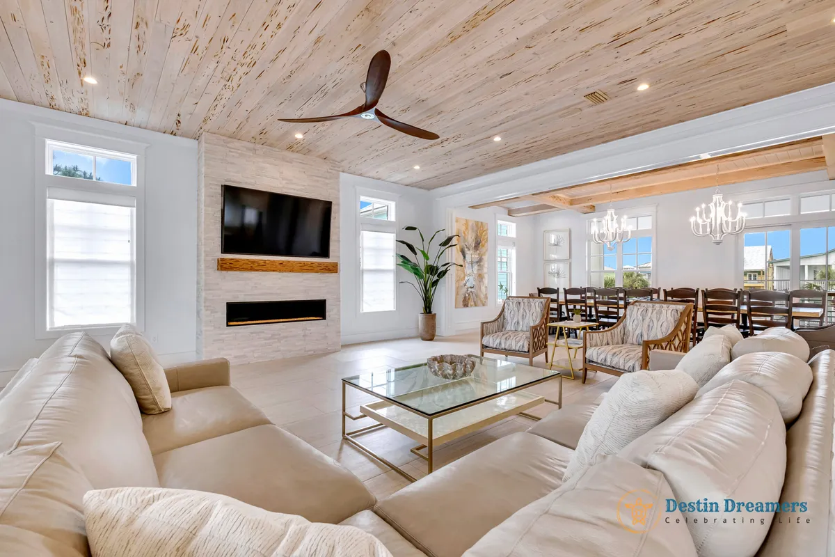 A cozy and inviting living area featuring a large sectional sofa, chandelier, flat-screen TV, and dining table set within a spacious interior. Natural light streams in, enhancing the atmosphere for movie nights or relaxing with loved ones.
