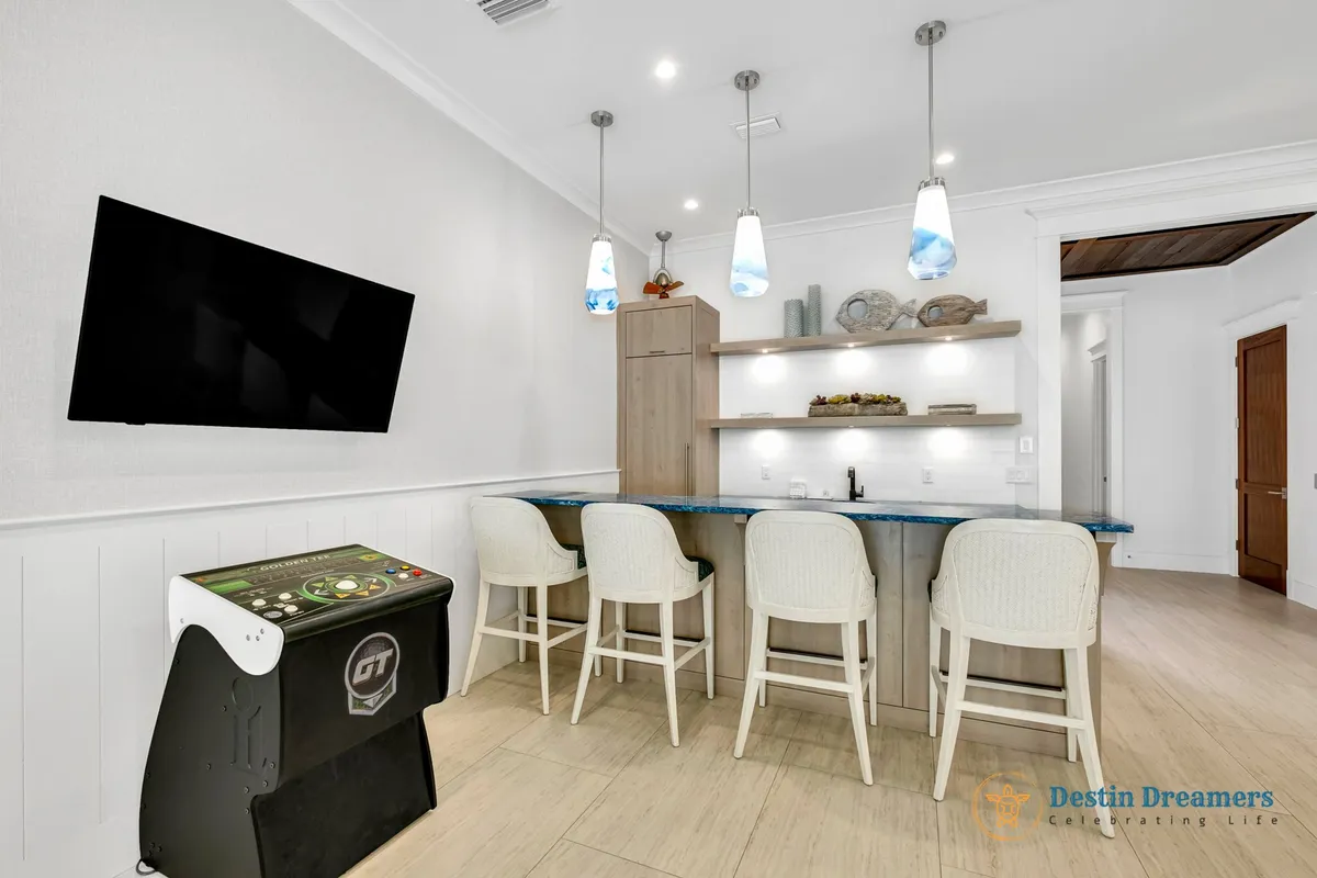A cozy bar area equipped with pendant lighting, an entertainment console, and modern barstools. The space invites guests to gather for drinks, conversation, and games, reinforcing the first floor as a social hub.
