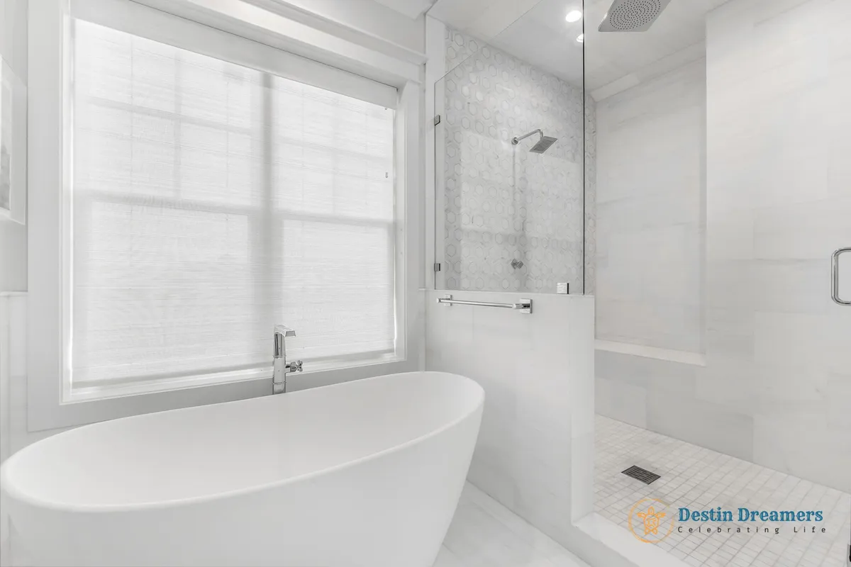 A spa-like bathroom features a freestanding modern bathtub, a large window diffusing natural light, a walk-in glass shower with a bench, and a textured tile accent wall. The overall ambiance is calm and inviting, ideal for relaxation and rejuvenation.